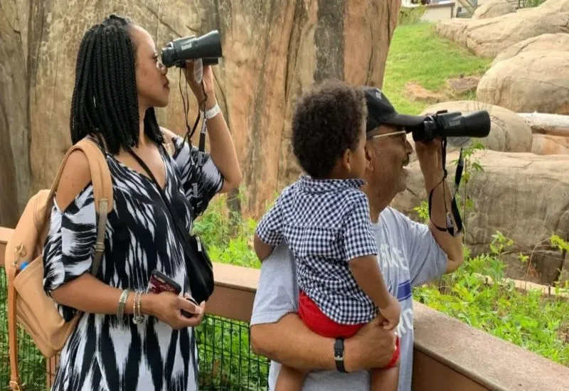 family using DMEI Binoculars at the OKC Zoo Family enjoying binoculars at Oklahoma City Zoo – Dean McGee Eye Institute Binocular Borrow Program.